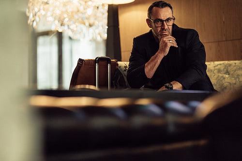 Businessman waiting at hotel lobby looking at camera