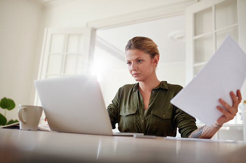 Female with documents working on laptop
