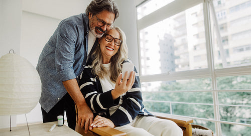 Senior couple use a smartphone together at home