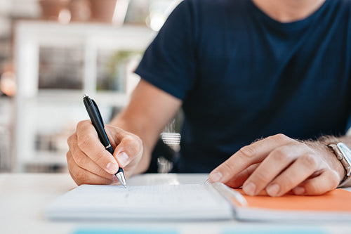 Hands of a young man writing in a office diary