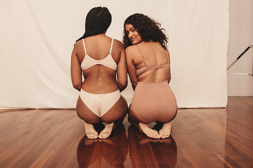 Two confident young women kneeling in underwear