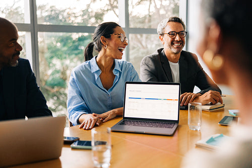 Business professionals laughing during a meeting at a conference table