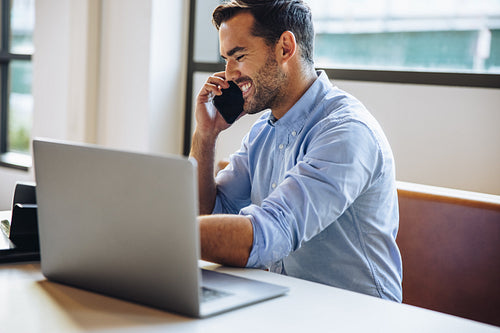 Cheerful businessman talking with client on cell phone
