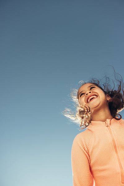 Adorable little girl laughing cheerfully at the beach