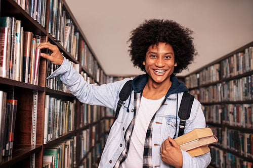 University student standing by bookshelf in the library