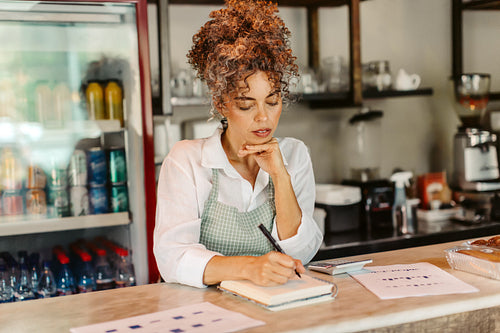 Female entrepreneur doing her budget in her cafe