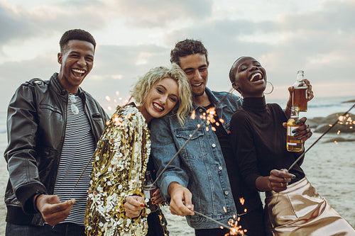Group of friends celebrating with fireworks at beach