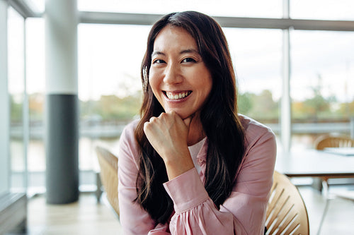 Smiling woman in office with hand on chin
