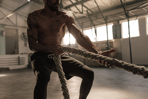 Athlete doing exercises with rope at gym