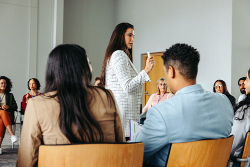 Businesswoman gesturing while talking during a presentation in front of a diverse group of colleagues