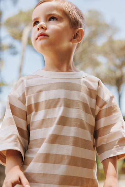 Young boy outdoors wearing a striped shirt with a peaceful expression