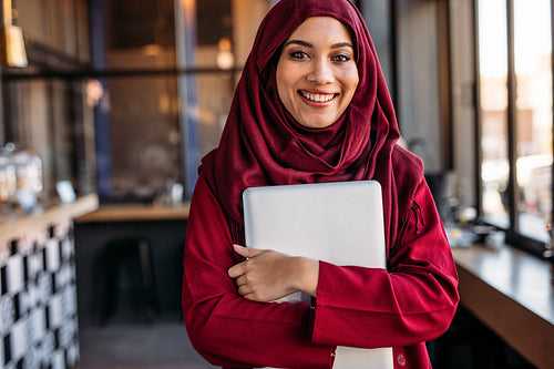 Muslim female standing with laptop at coffee shop