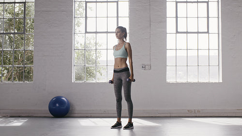 Woman doing lateral raises with hand weights at fitness studio