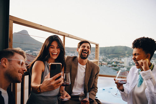 Friends sharing a joyous evening on a balcony with scenic mountain views