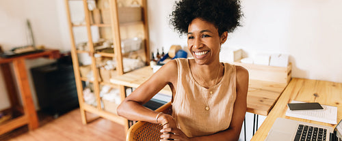 Cheerful business owner sitting in jewelry workshop