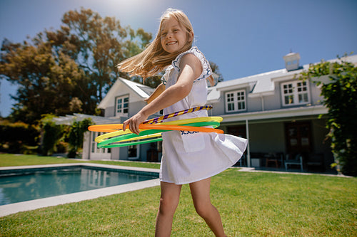 Smiling girl playing with hula hoop outdoors