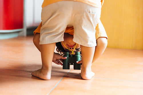 Happy child playing with binoculars indoors and enjoying exploration and curiosity