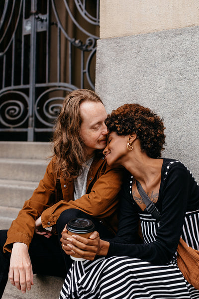 Affectionate embrace on city steps with coffee in hand