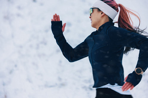 Woman sprinting through snowy landscape building stamina in winter training