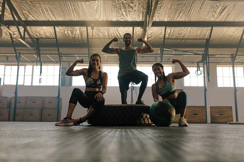 Young people posing and flexing their muscles in gym
