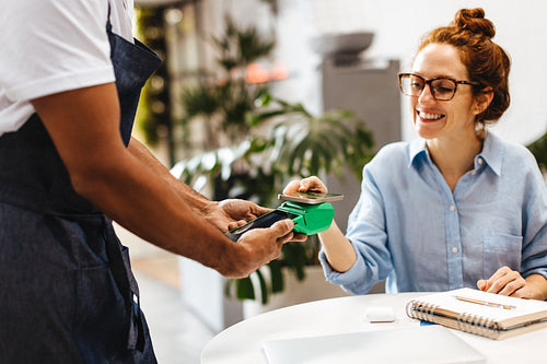 Cafe customer making a contactless payment with her smartphone
