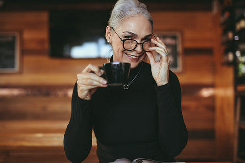 Charming senior woman at cafe having coffee