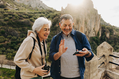 Happy elderly couple having a video call while hiking outdoors