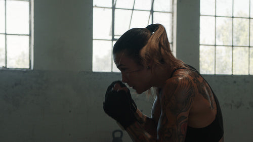 Female boxer practising shadow boxing in gym