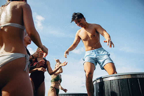 Young man exits ice bath with friends cheering outdoors in wellness ritual