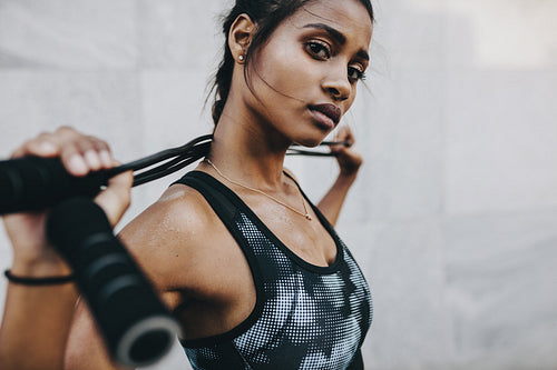 Portrait of a fitness woman standing with a skipping rope on her neck