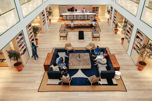 Bird's-eye view of a modern business lounge with people engaged in casual meetings and activities