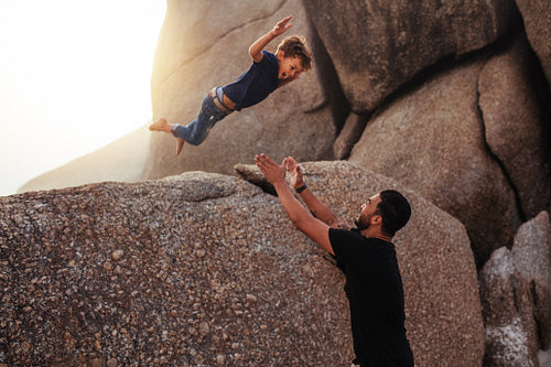 Little boy leaping into his father's arms at the beach