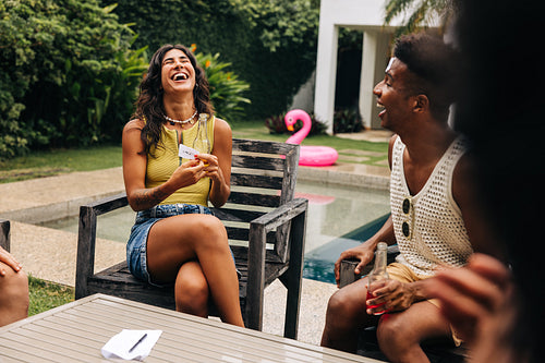 Friends playing charades and laughing by pool