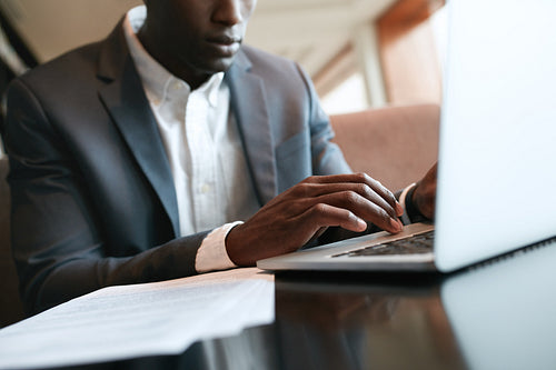 African businessman working on laptop at cafe