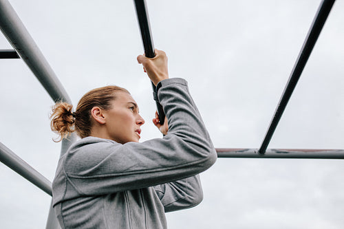 Athletic woman exercising outdoor on fitness equipments