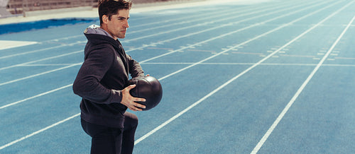 Athlete training with a medicine ball on running track