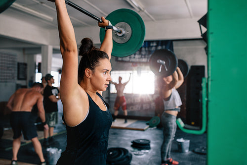 Muscular woman exercising with barbell in a gym