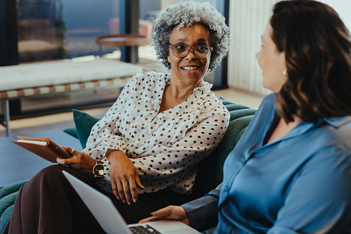 Women discussing business strategy in modern office lounge