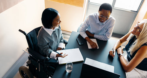 Diverse professionals having a meeting around a table with a laptop