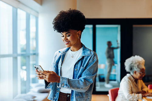 Young woman using phone in modern office