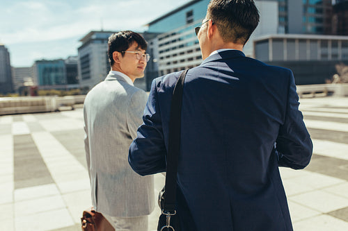Two businessmen talking and walking in the city