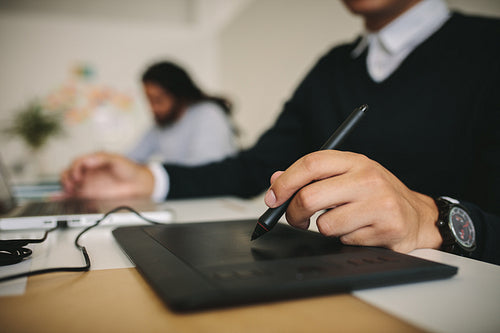 Close up of a man writing on a digital writing pad
