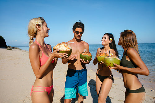 Friends drinking fresh coconut water by the sea