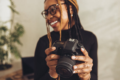 Woman holding a dslr camera in her workspace
