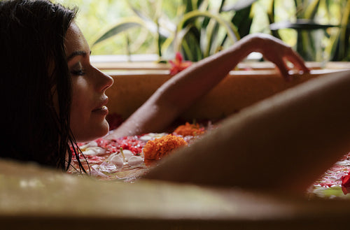 Woman relaxing in flower bath tub at day spa.