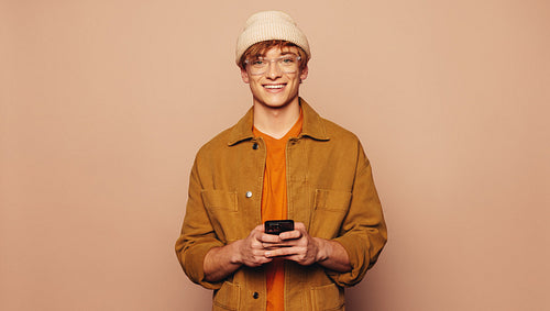 Casual man on peach background using smartphone