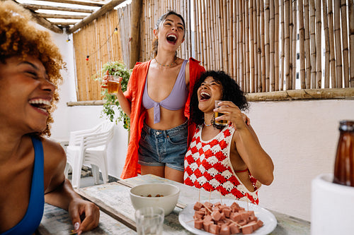 Three friends enjoying drinks, singing, and snacking outdoors in Rio de Janeiro