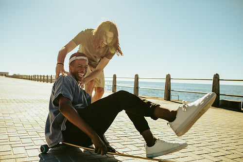 Boys enjoying with a longboard on a seaside road