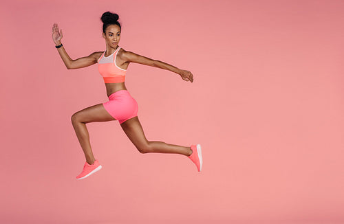 Healthy african woman sprinting on pink background