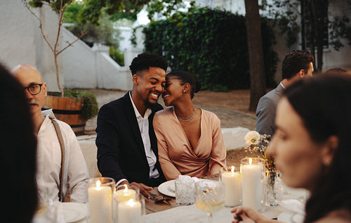 Couple sharing a loving moment at an elegant outdoor wedding with friends